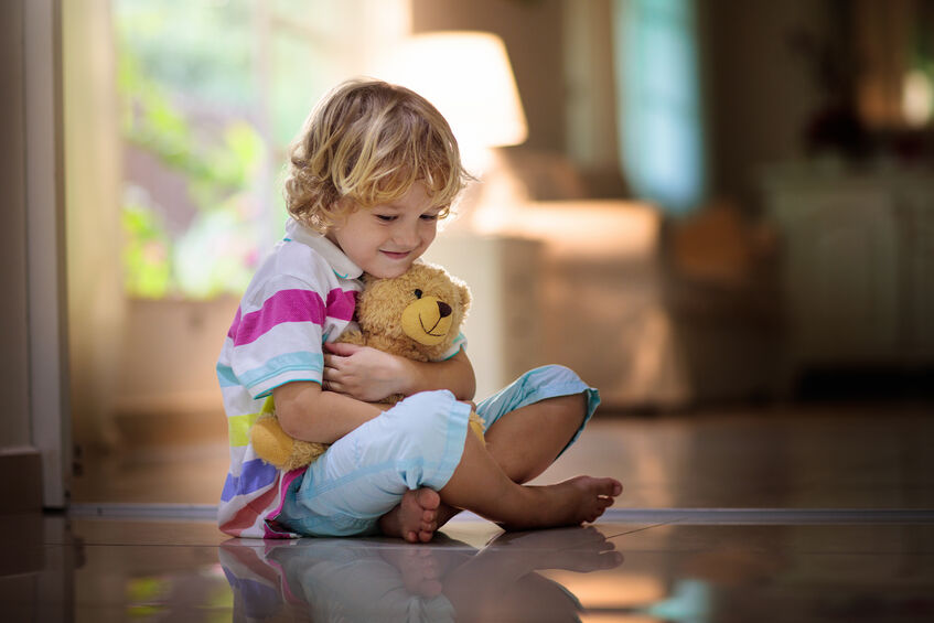 child playing with teddy bear on floor