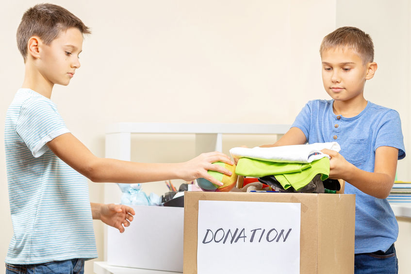 Kids volunteers sorting toys, clothes, books, donation goods in donate charity boxes indoors