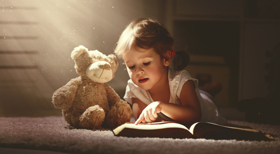 little girl reading to her teddy bear