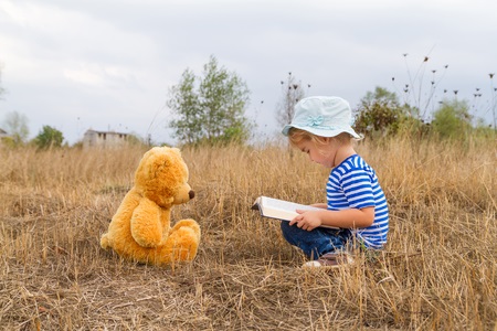 girl reading book teddy bear