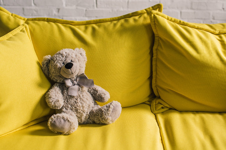 stuffed bear on yellow couch