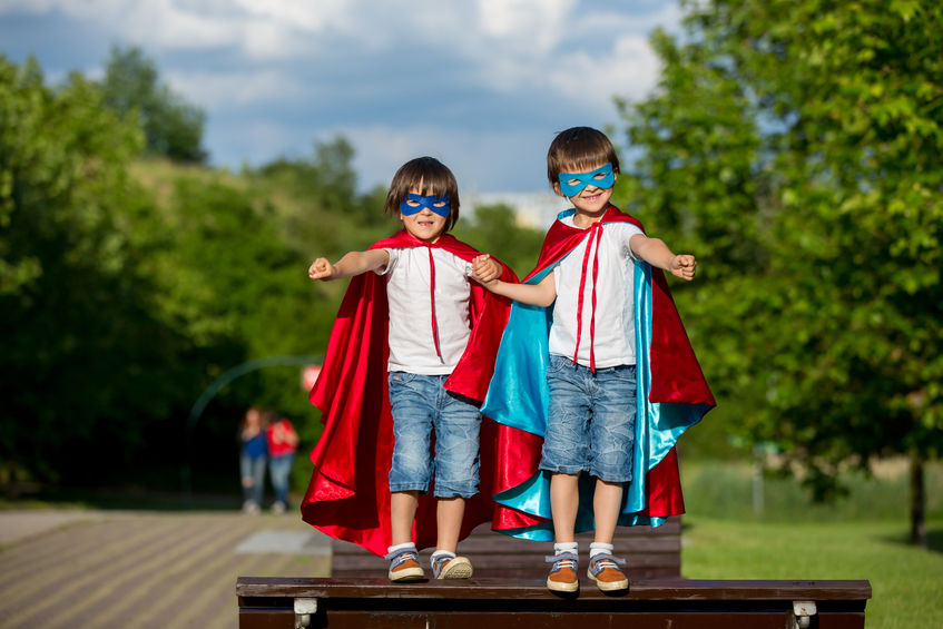 Two sweet little preschool children, boys, playing superhero in the park, summertime