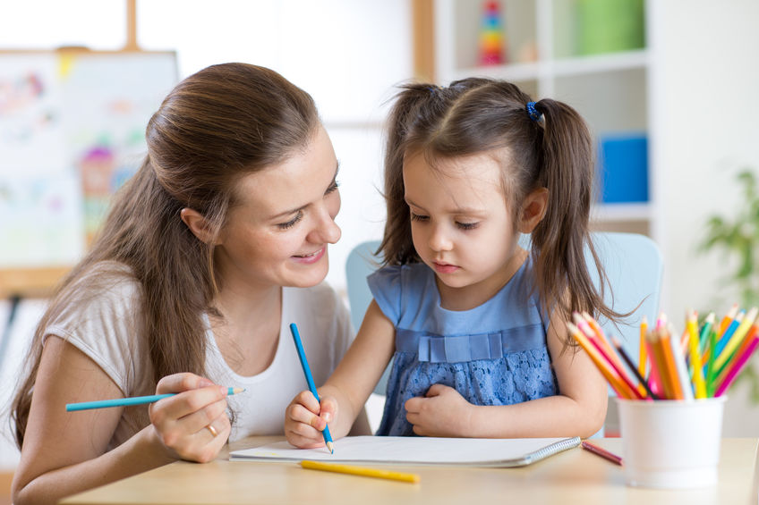 babysitter helping child color a drawing