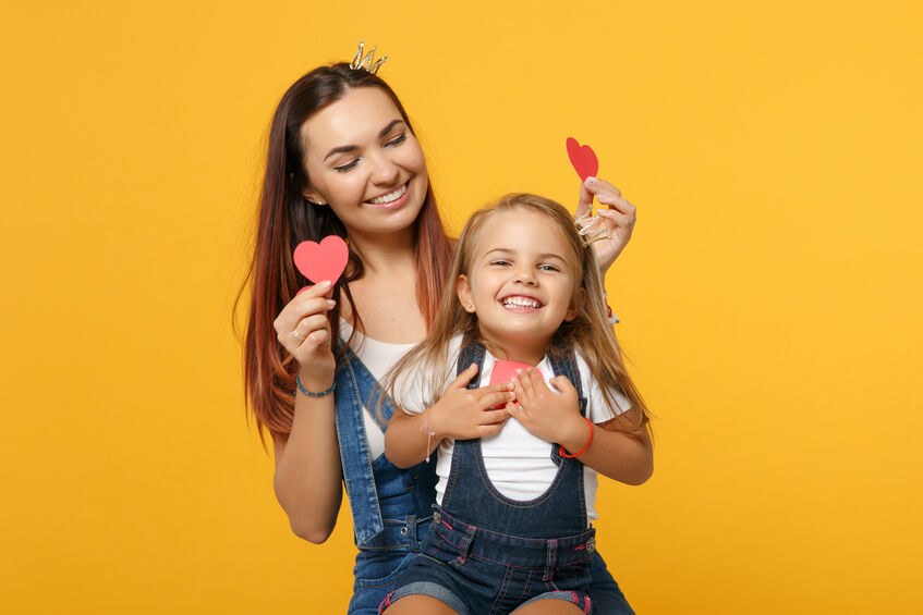 mother and daughter holding up valentines day hearts