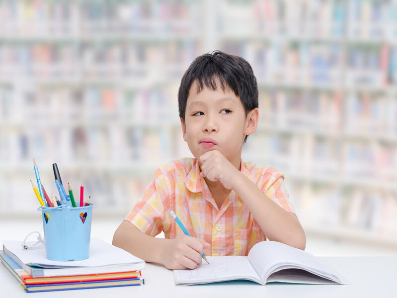young boy thinking while working on homework