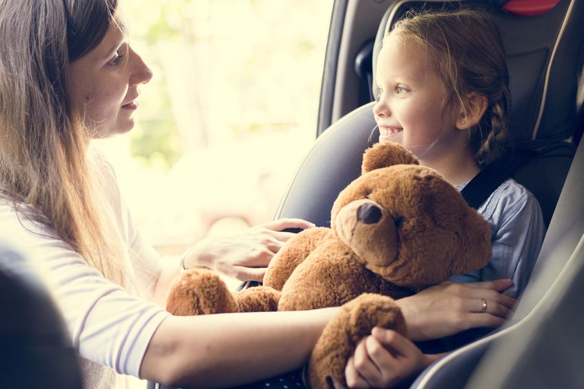 Mother helping to put on the seat belt for child