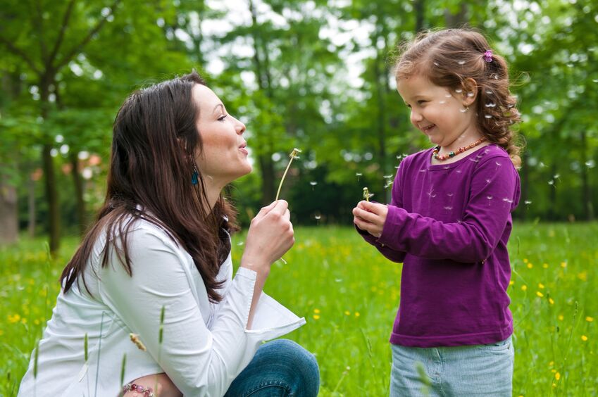 mother with small daughter blowing to dandelion