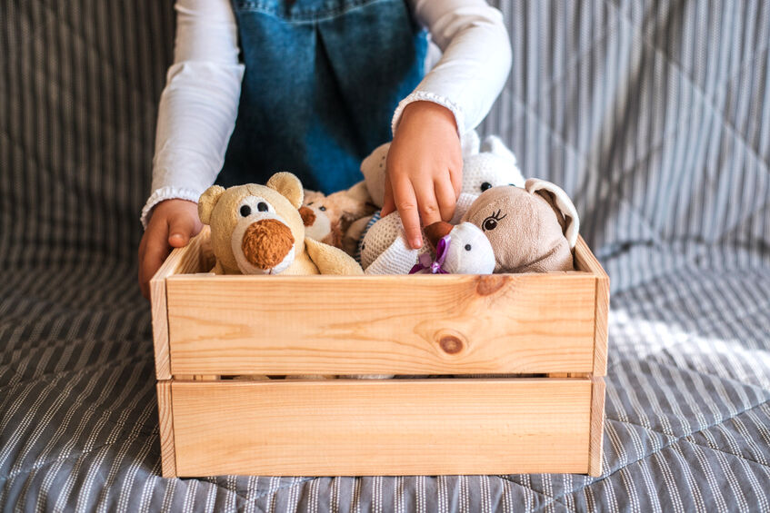 young girl kneeling in front of box full of stuffed animals