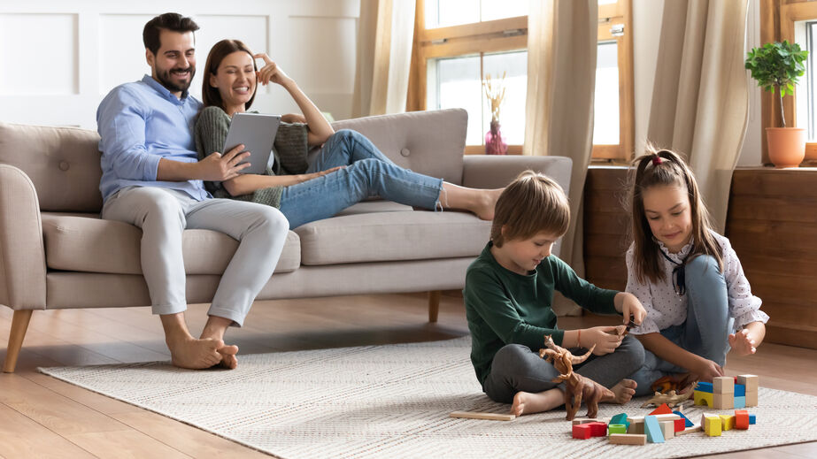 young parents watching their children play in the living room