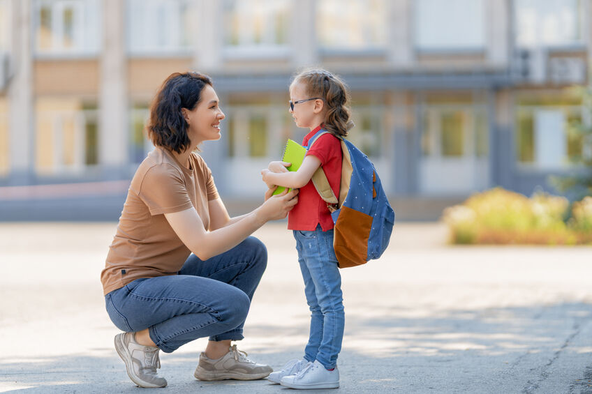 mother talking to daughter as she waits for schoolbus