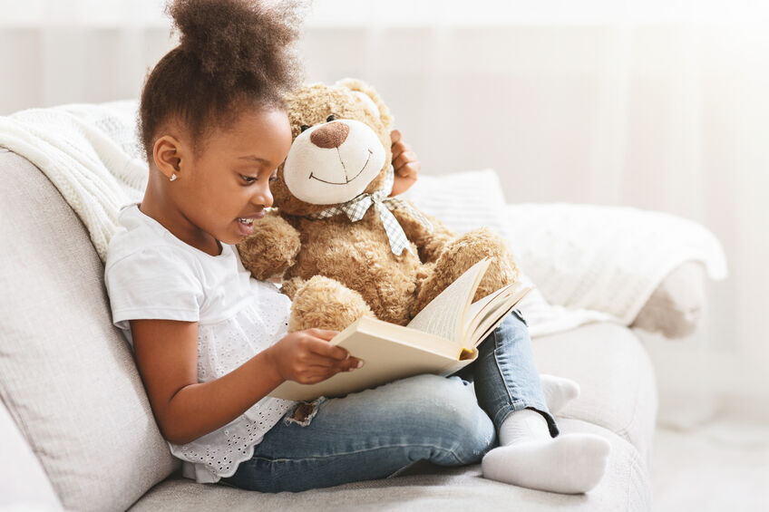 young girl reading to stuffed animal