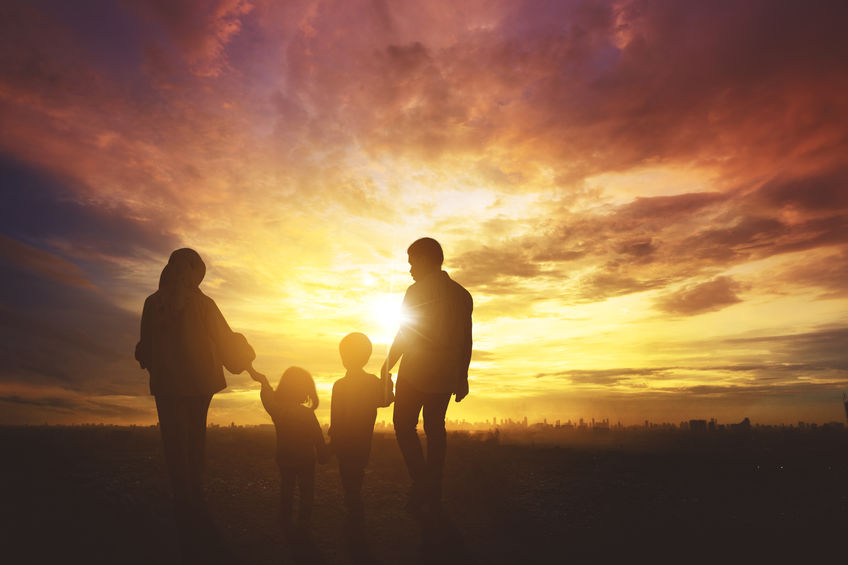 family holding hands in front of sunset